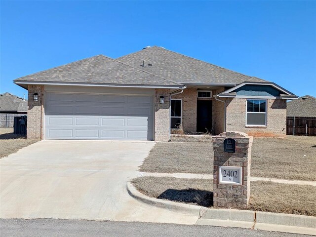 2402 Cattail Cir, Midwest City, OK 73130 - ranch-style house featuring roof with shingles, brick siding, concrete driveway, fence, and a garage