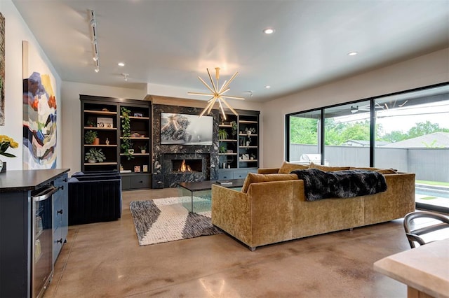 living area featuring built in shelves, a fireplace, finished concrete flooring, recessed lighting, and beverage cooler