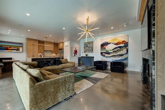 living area with a notable chandelier, recessed lighting, concrete floors, a fireplace, and baseboards