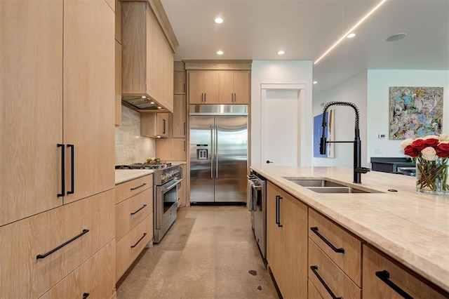 kitchen with custom exhaust hood, high end appliances, recessed lighting, light brown cabinets, and a sink