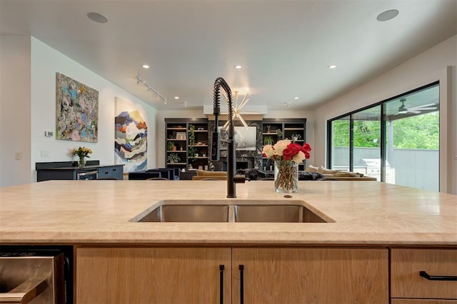 kitchen with open floor plan, a sink, light stone countertops, track lighting, and recessed lighting