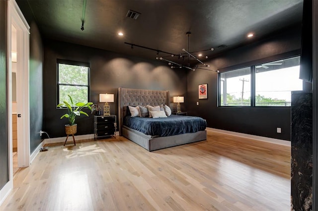 bedroom featuring multiple windows, visible vents, and wood finished floors