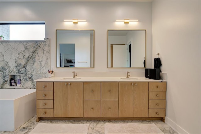 bathroom featuring double vanity, marble finish floor, a freestanding bath, and a sink