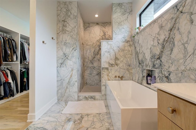 full bathroom with recessed lighting, marble finish floor, a spacious closet, a marble finish shower, and a bath