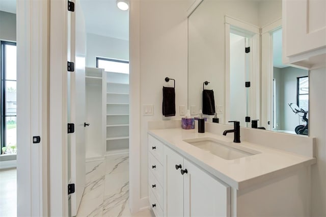 bathroom with marble finish floor, vanity, and a spacious closet