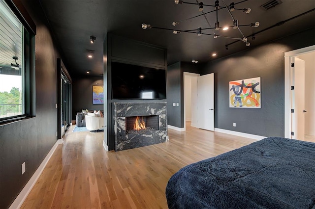 bedroom featuring baseboards, a fireplace, visible vents, and wood finished floors