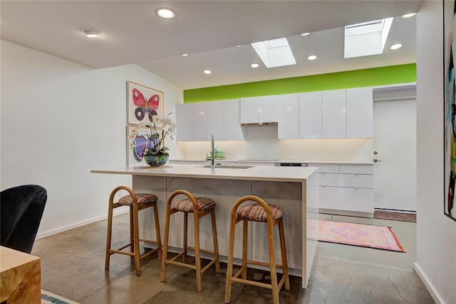 kitchen featuring concrete floors, modern cabinets, a breakfast bar area, and a sink