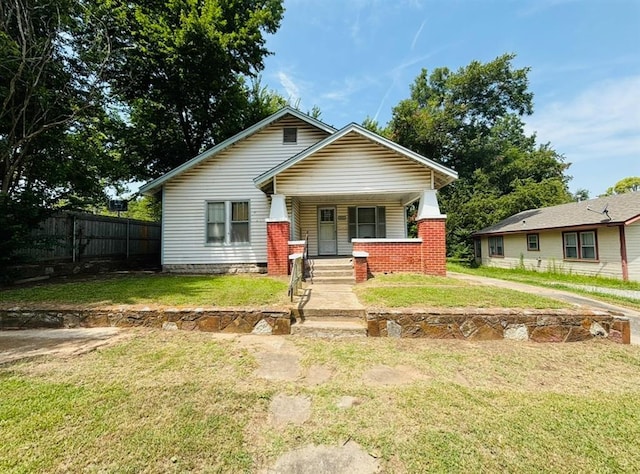 bungalow featuring a porch, a front yard, and fence