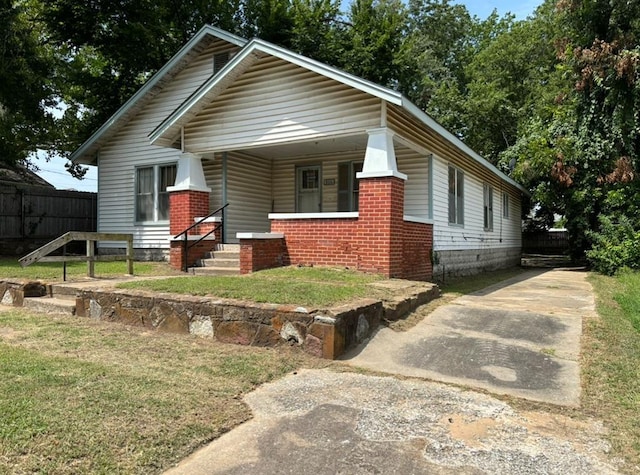 view of front of property featuring a porch, fence, a front lawn, and concrete driveway