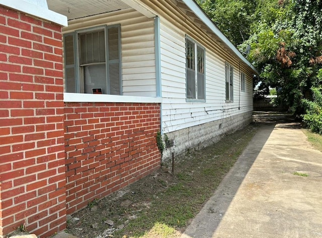 view of home's exterior featuring concrete driveway and brick siding