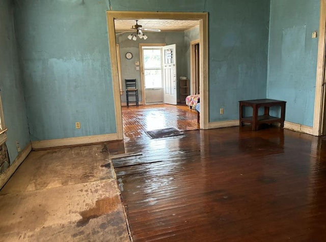 interior space with a ceiling fan, hardwood / wood-style flooring, and baseboards