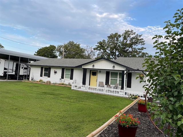 ranch-style home featuring a porch, a front yard, and roof with shingles