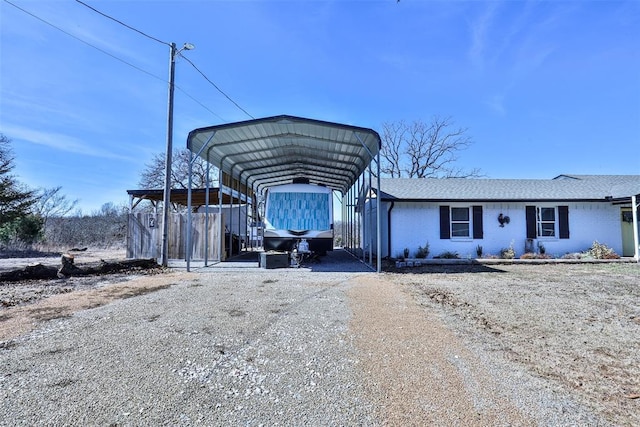 view of front facade featuring brick siding, dirt driveway, and roof with shingles