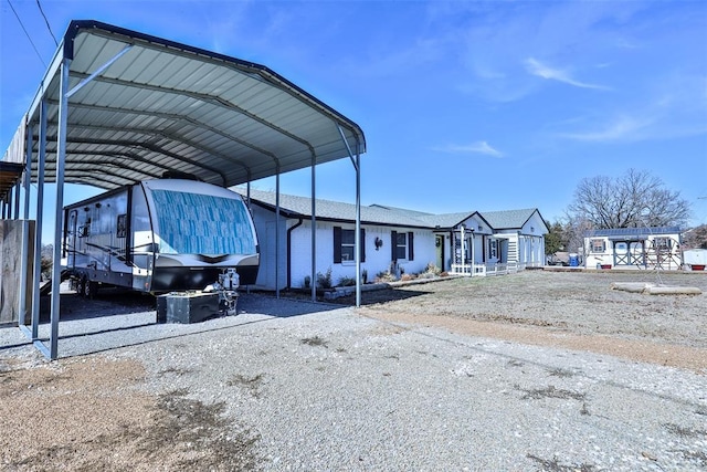 view of vehicle parking with gravel driveway and a carport