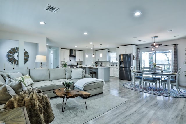 living area with recessed lighting, visible vents, and light wood finished floors