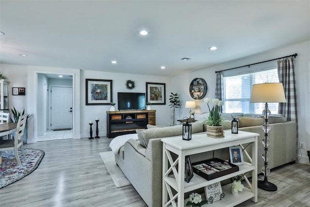 living room with visible vents, baseboards, light wood-style flooring, and recessed lighting