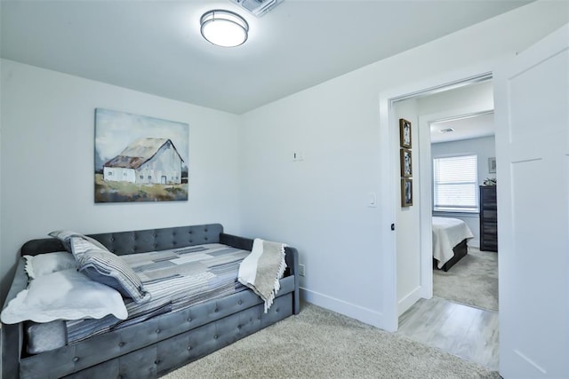 carpeted living area featuring baseboards, visible vents, and wood finished floors