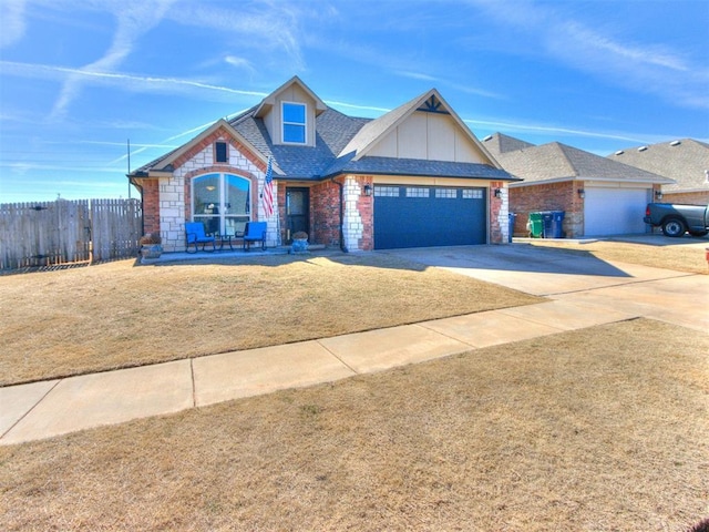 craftsman-style house with a garage, concrete driveway, roof with shingles, fence, and a front yard