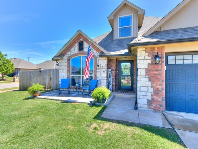 property entrance with roof with shingles, a lawn, brick siding, fence, and stone siding