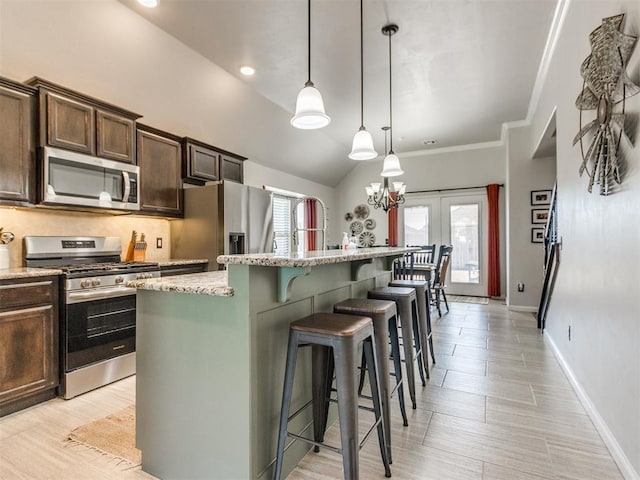 kitchen with appliances with stainless steel finishes, light stone countertops, a kitchen island with sink, and dark brown cabinetry