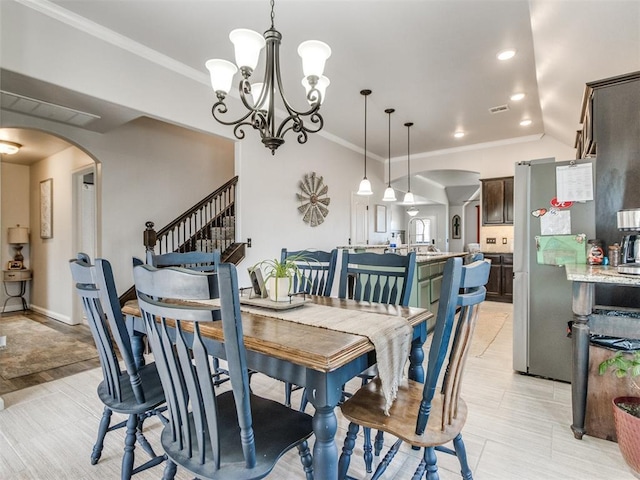 dining space featuring an inviting chandelier, arched walkways, visible vents, and ornamental molding