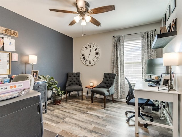 office space with baseboards, a ceiling fan, and light wood-style flooring