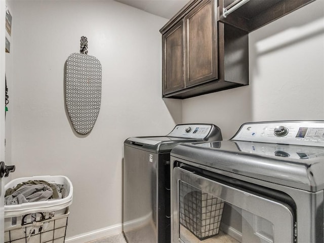 washroom featuring cabinet space, baseboards, and washer and dryer
