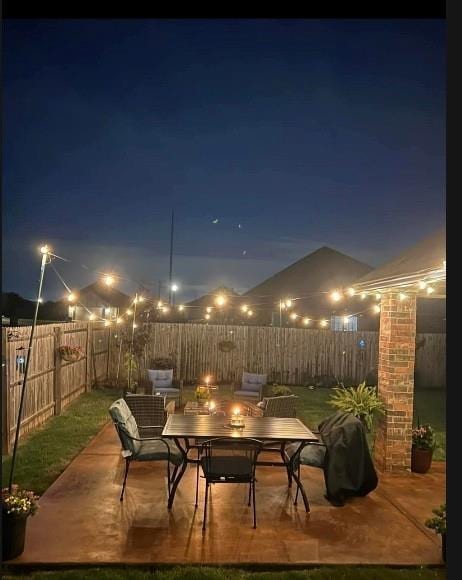 patio at twilight featuring outdoor dining space and a fenced backyard