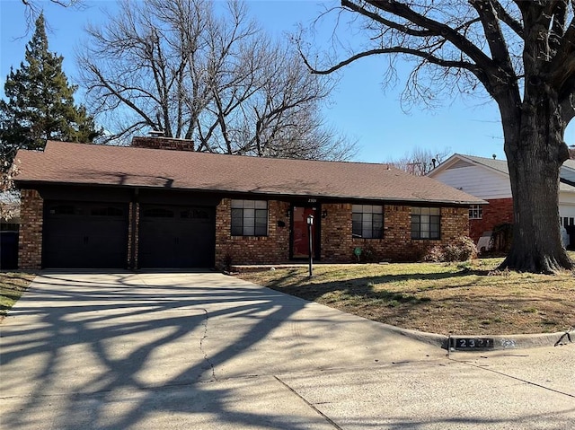 ranch-style house featuring a garage, a shingled roof, concrete driveway, a chimney, and brick siding