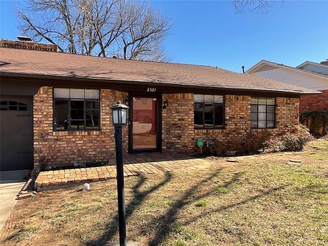 view of front of home featuring a shingled roof, brick siding, and an attached garage