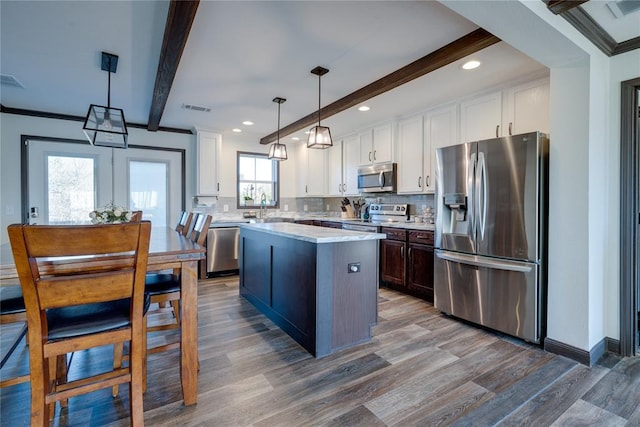 kitchen with stainless steel appliances, visible vents, light countertops, beam ceiling, and decorative backsplash