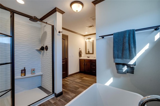 bathroom featuring visible vents, ornamental molding, wood finished floors, vanity, and a shower stall