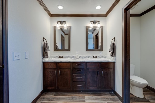 bathroom featuring double vanity, baseboards, toilet, wood finished floors, and a sink