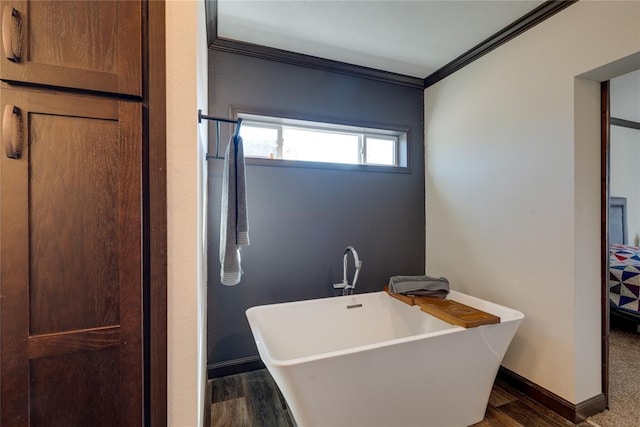 full bathroom with a soaking tub, baseboards, ornamental molding, and wood finished floors