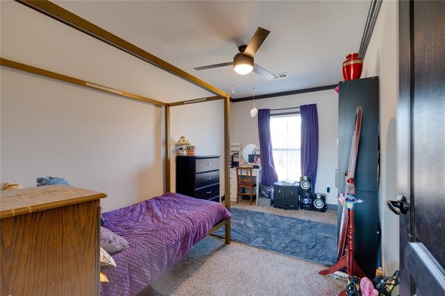 carpeted bedroom with ornamental molding, visible vents, and a ceiling fan