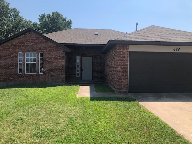 ranch-style home with brick siding, roof with shingles, concrete driveway, an attached garage, and a front yard