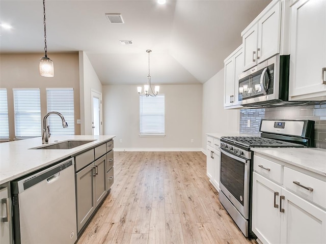 kitchen with stainless steel appliances, a sink, visible vents, vaulted ceiling, and tasteful backsplash