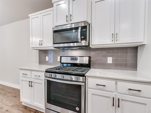 kitchen with stainless steel appliances, white cabinetry, and light wood-style floors