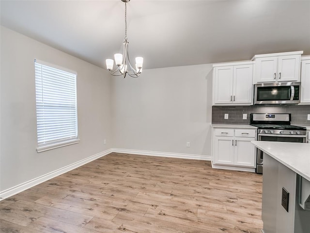 kitchen with light wood-type flooring, stainless steel appliances, decorative backsplash, and light countertops