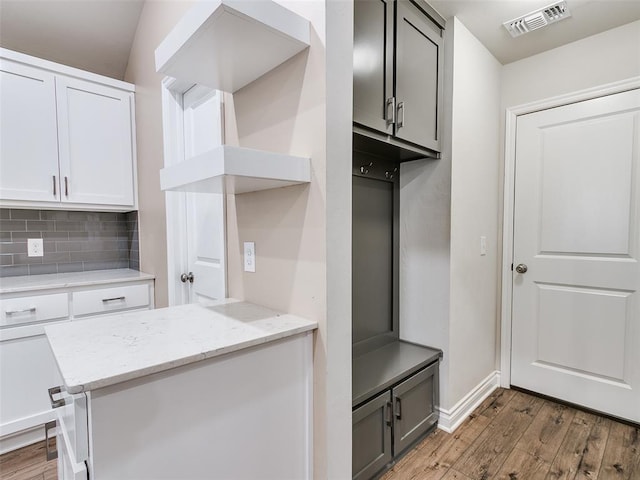 mudroom featuring light wood finished floors, visible vents, and baseboards