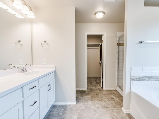 bathroom featuring a stall shower, a spacious closet, vanity, and a bath