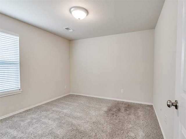 unfurnished room with carpet, visible vents, and baseboards