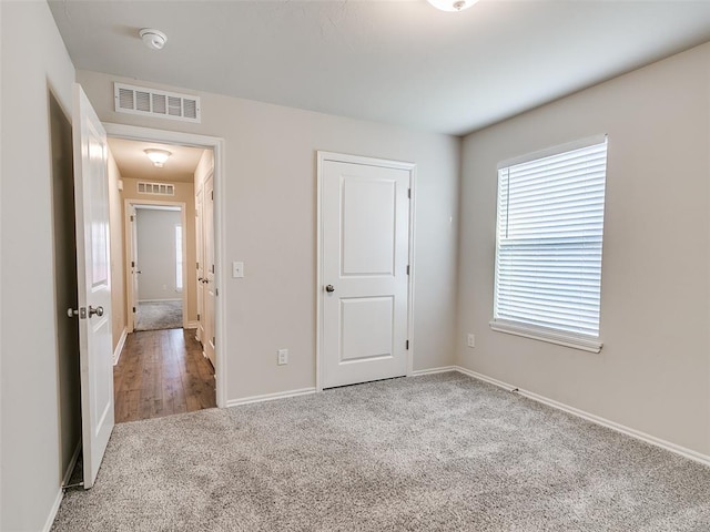 unfurnished bedroom featuring carpet, visible vents, and baseboards