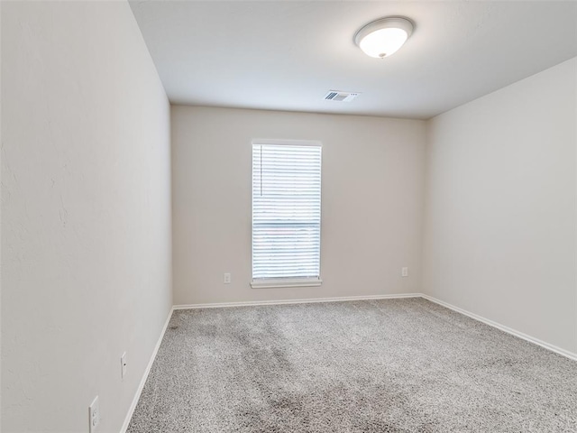 empty room featuring carpet, visible vents, and baseboards