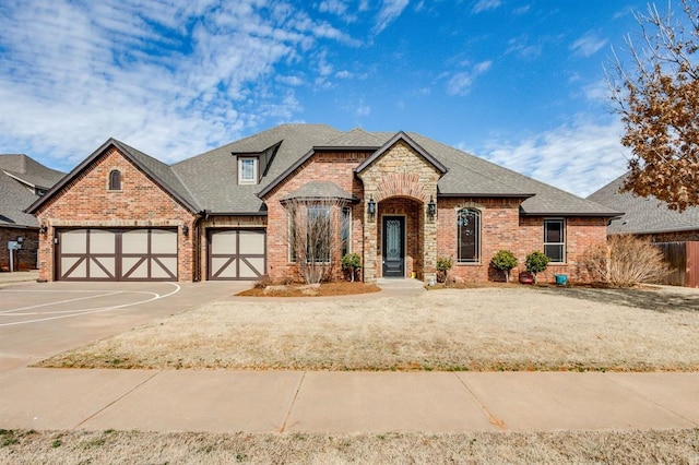 french provincial home featuring driveway, brick siding, roof with shingles, and an attached garage