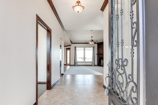 entryway featuring light tile patterned floors, ceiling fan, ornamental molding, and baseboards