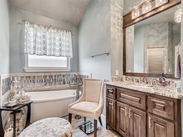 full bathroom featuring a freestanding tub, vanity, and wood finished floors