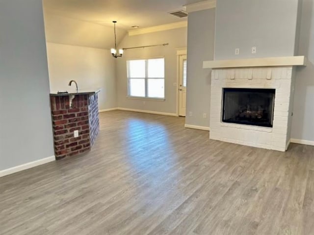 18816 Havenbrook Rd, Edmond, OK 73012 - unfurnished living room featuring baseboards, a chandelier, wood finished floors, a fireplace, and lofted ceiling