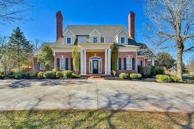 neoclassical / greek revival house featuring brick siding and a chimney