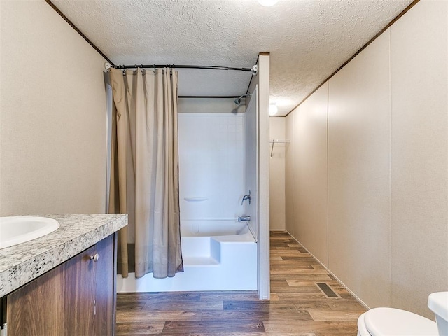 full bathroom featuring shower / tub combo, toilet, wood finished floors, a textured ceiling, and vanity